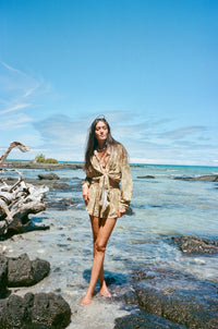 Woman standing on a rocky beach with ocean and sky in the background